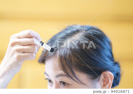 伸びてきた白髪に色を塗る中年女性 グレイヘアへの移行 伸びてきた白髪に色を塗る中年女性 グレイヘアへの移行 94916871