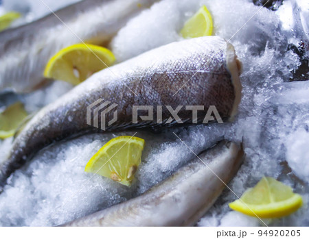 Fresh raw sea fish and lemon peces on ice surface. Fresh raw sea fish and lemon peces on ice surface. 94920205