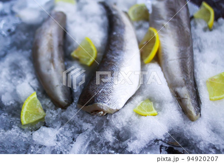 Fresh raw sea fish and lemon peces on ice surface. Fresh raw sea fish and lemon peces on ice surface. 94920207