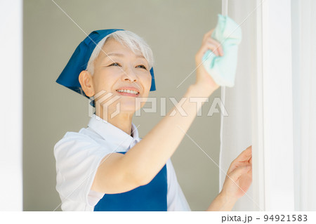 窓拭きをするハウスキーパーのシニア女性 94921583