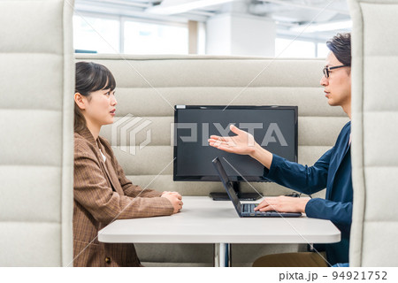 プライベートブースで話をするビジネスマンとビジネスウーマン プライベートブースで話をするビジネスマンとビジネスウーマン 94921752
