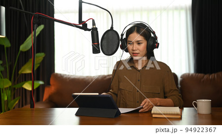 Attractive woman using laptop and microphone streaming audio podcast at home studio. Communication and technology concept 94922367