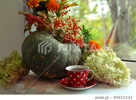 Vintage still life with pumpkins and decorations, flowers and cup of tea on the window ceiling inside, thanksgiving day background, fall calendar season concept 94922532