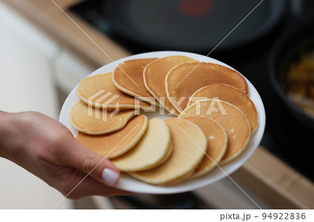 A woman's hand holds a white plate with pancakes A woman's hand holds a white plate with pancakes 94922836