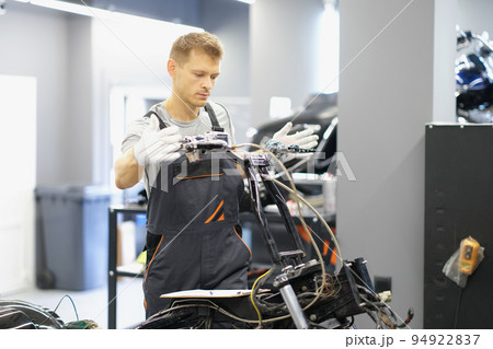 A man mechanic repairs the steering wheel of a motorcycle A man mechanic repairs the steering wheel of a motorcycle 94922837