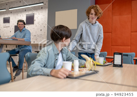 Boy taking a seat for lunch in the school canteen 94923455