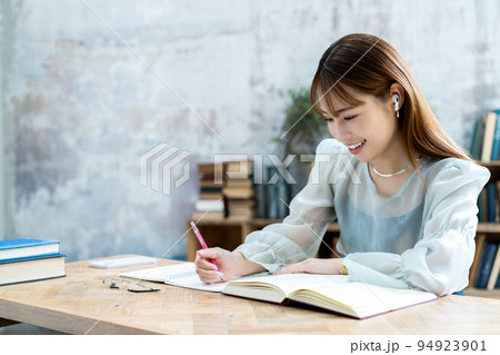 イヤホンをして勉強する若い女性 イヤホンをして勉強する若い女性 94923901