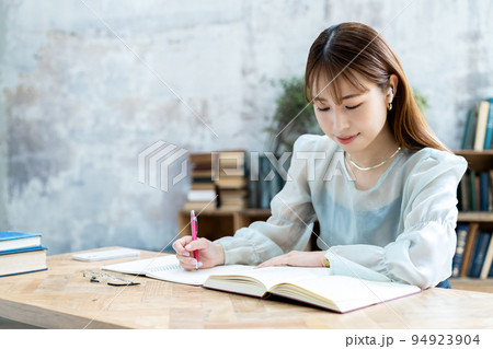 イヤホンをして勉強する若い女性 イヤホンをして勉強する若い女性 94923904