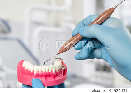 Dentist's hands with layout of the human jaw and dental instrument. Dentist's hands with layout of the human jaw and dental instrument. 94925431