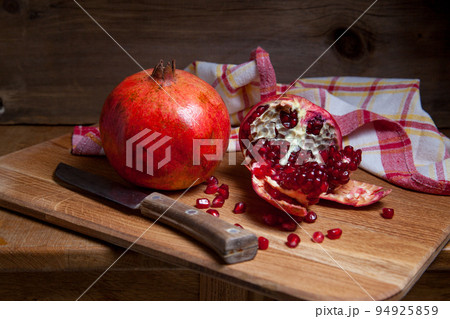 Fresh red pomegranate with vintage knife on a wooden background.. 94925859