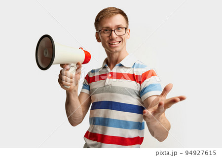 Portrait of young man in glasses posing with megaphone isolated over white studio background. Good proposal 94927615