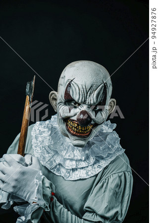 creepy evil clown lifts a blood-stained axe 94927876