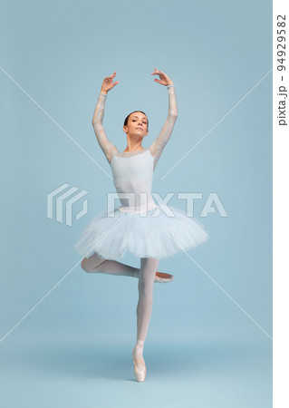 Portrait of tender, beautiful, young ballerina dancing, performing isolated over blue studio background. Femininity 94929582