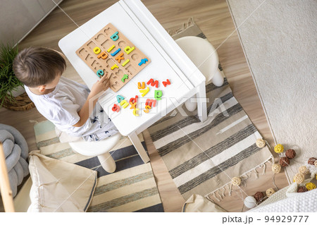 Male kid playing with wooden eco friendly alphabet letters board on table top view intellectual game 94929777
