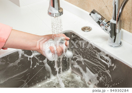 Washing off the foam from the cleaning sponge in the female hand with tap water Washing off the foam from the cleaning sponge in the female hand with tap water 94930284