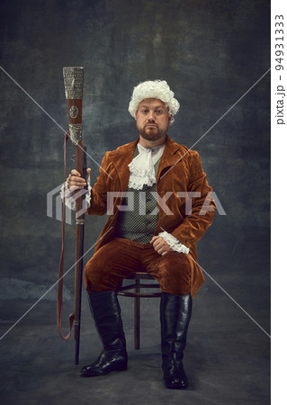 Creative portrait of retro style hunter in vintage hunting clothing with old gun isolated over dark background. Art, fashion, emotions, traditions, hobby concept 94931333