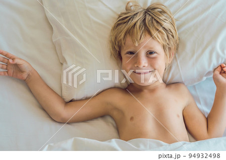 Smiling boy in bed waking up in his bed 94932498