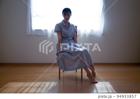 光の差し込む部屋で椅子に座った女性 光の差し込む部屋で椅子に座った女性 94933857