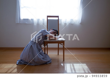 光の差し込む部屋で椅子にもたれる女性 94933859
