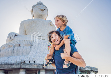 Father and son tourists on the Big Buddha statue. Was built on a high hilltop of Phuket Thailand Can be seen from a distance Father and son tourists on the Big Buddha statue. Was built on a high hilltop of Phuket Thailand Can be seen from a distance 94934019