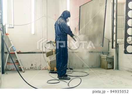 worker powder coats steel parts in a spray booth worker powder coats steel parts in a spray booth 94935052
