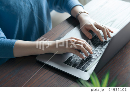 テーブルの上でノートPCを操作する女性  94935101