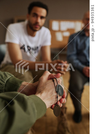 Hands of guy with post traumatic syndrome holding chain with two medallions Hands of guy with post traumatic syndrome holding chain with two medallions 94935361