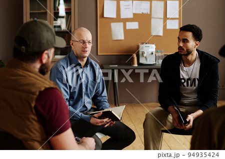 Confident mature male counselor consulting people with post traumatic syndrome 94935424