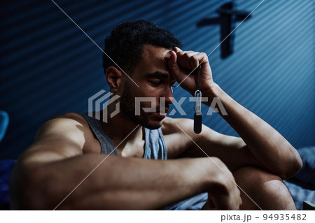 Young unhappy man with post traumatic syndrome holding chain with medallion 94935482
