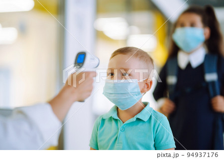 Nurse or doctor checks children body temperature using infrared forehead thermometer for virus. Nurse or doctor checks children body temperature using infrared forehead thermometer for virus. 94937176