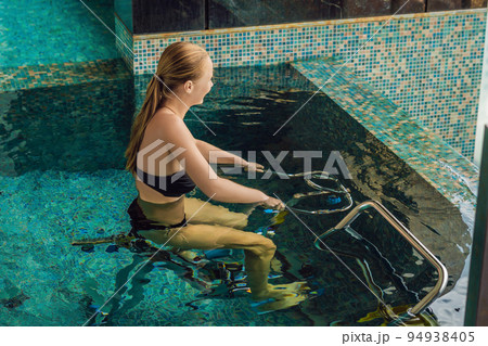Young woman on bicycle simulator underwater in the pool 94938405