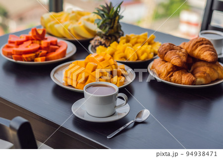 Breakfast table with coffee fruit and bread croisant on a balcony against the backdrop of the big city 94938471
