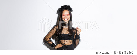 Image of beautiful asian woman in halloween costume, showing credit card and smiling, standing in gothic lace dress over white background Image of beautiful asian woman in halloween costume, showing credit card and smiling, standing in gothic lace dress over white background 94938560