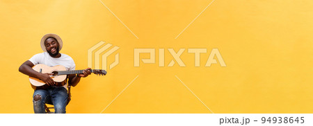 Full-length photo of excited artistic man playing his guitar. Isolated on yellow background. Full-length photo of excited artistic man playing his guitar. Isolated on yellow background. 94938645