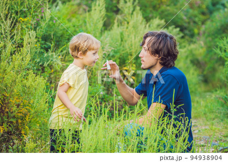 Father and son use a spray from an allergy because of an allergy to ragweed 94938904