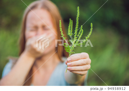 Young woman sneezes because of an allergy to ragweed Young woman sneezes because of an allergy to ragweed 94938912