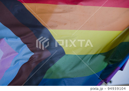Close-Up rainbow gay pride flag outside on a street. Symbol of the Lesbian Bisexual Transgender LGBT community waving in wind against cloudy sky. Social movement for freedom and equliaty. Copy Space Close-Up rainbow gay pride flag outside on a street. Symbol of the Lesbian Bisexual Transgender LGBT community waving in wind against cloudy sky. Social movement for freedom and equliaty. Copy Space 94939104