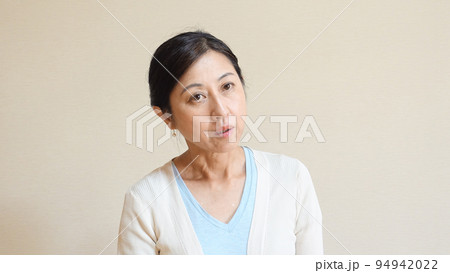 ぼんやりした表情で首をかしげる中年女性 94942022