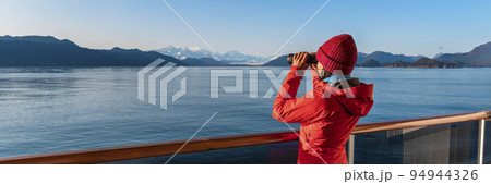 Alaska Glacier Bay cruise ship passenger looking at mountains with binoculars exploring Glacier Bay National Park. Woman on travel Inside Passage enjoying view. Panoramic vacation adventure banner. 94944326