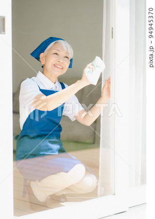 窓拭きをするハウスキーパーのシニア女性 94945370