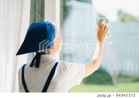 窓拭きをするハウスキーパーのシニア女性 94945372