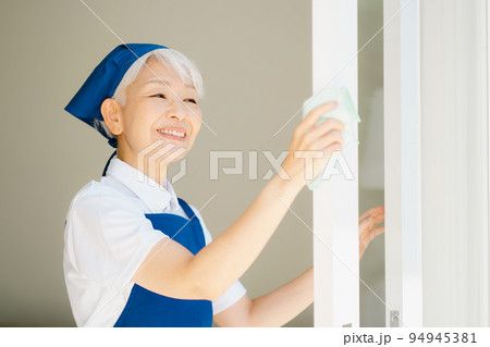 窓拭きをするハウスキーパーのシニア女性 94945381
