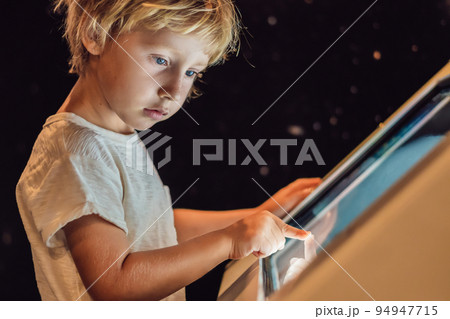 The boy uses the touch screen in the dark The boy uses the touch screen in the dark 94947715