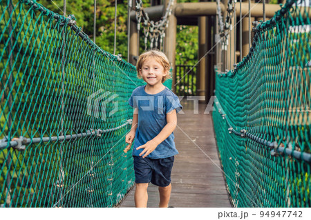 The boy is running on a suspension bridge in Kuala Lumpur, Malaysia 94947742