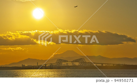 冬2月 舞浜海岸からダイヤモンド富士直前の夕陽に染まる富士山・ゲイトブリッジと羽田離陸の飛行機 94950271