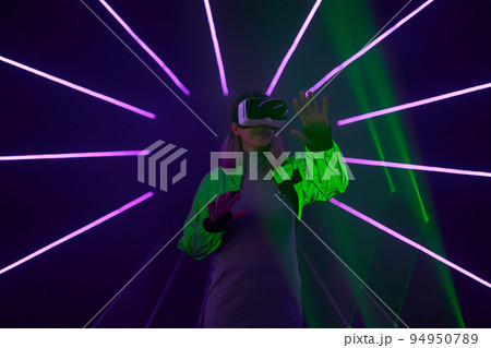 Woman is using virtual reality headset to access in metaverse. Woman is using virtual reality headset to access in metaverse. 94950789