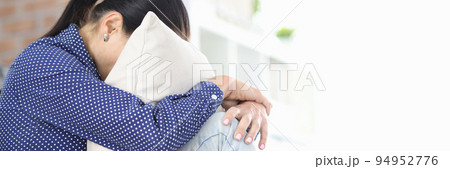 Upset woman sits with head buried in pillow Upset woman sits with head buried in pillow 94952776