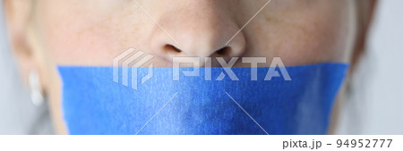 Woman mouth is sealed with blue tape closeup 94952777