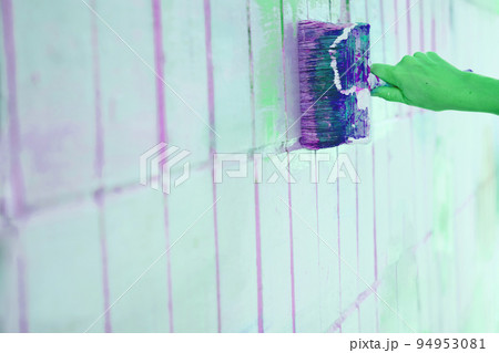 Brush painting dyeing surface with green purple paint and green rubber gloves Brush painting dyeing surface with green purple paint and green rubber gloves 94953081