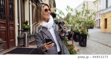 woman Tourist walks around the city sightseeing with a cup of coffee and a mobile phone woman Tourist walks around the city sightseeing with a cup of coffee and a mobile phone 94953275